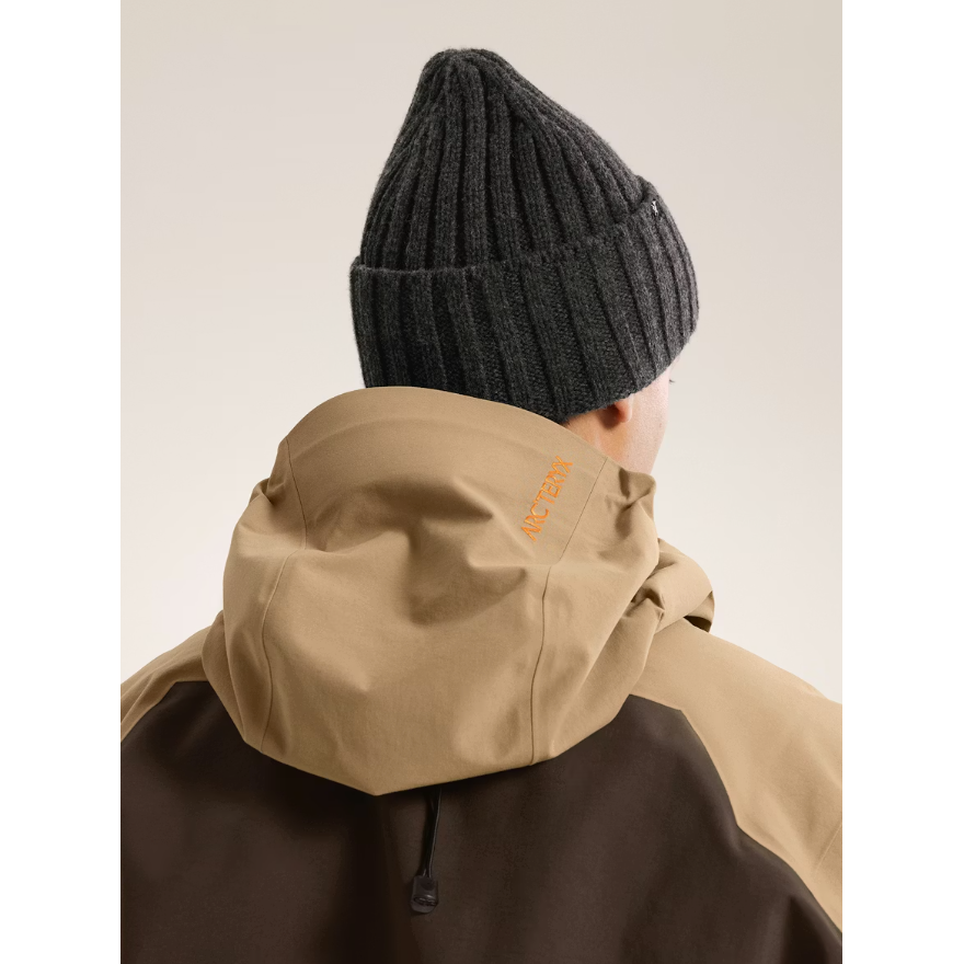 Back view of person wearing Arc'teryx Chunky Ribbed Toque beanie in black heather with tan jacket
